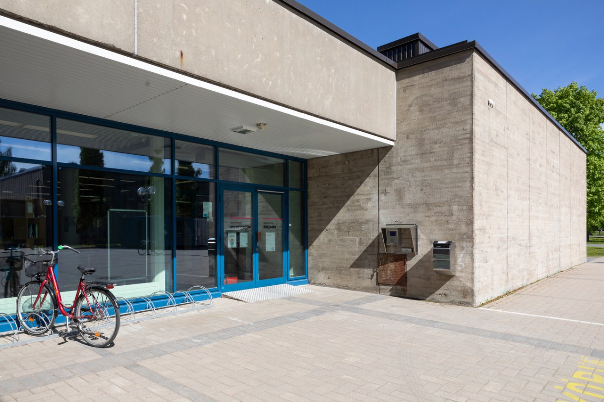 Grey concrete building. A bicycle is parked next to the entrance. 