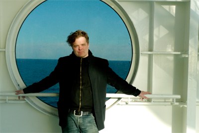 Muusikko Jukka Takalo pyöreän ikkunan edessä.
