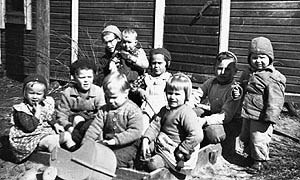Valokuva: Sisaruksia, serkkuja ja kylän lapsia Jonin kotitalon pihalla kesällä 1954.