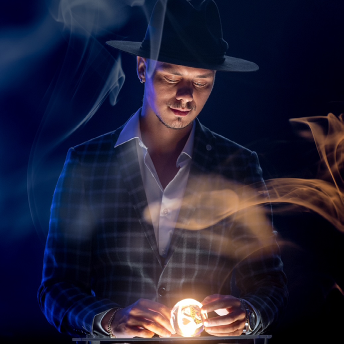 A man wearing a hat looks down at a light ball, surrounded by smoke