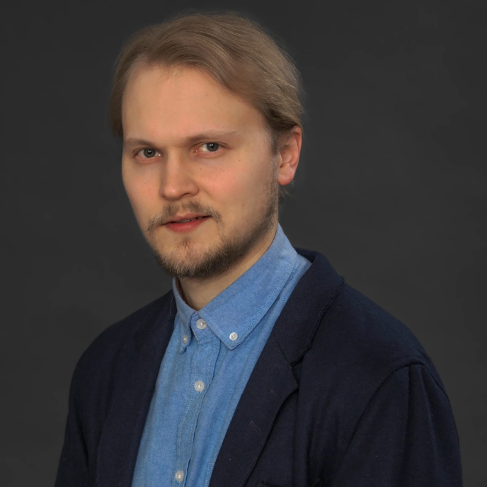 A man looks at the camera with a gray background